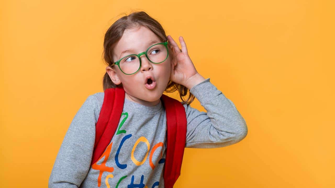 Niño con problemas de audición en clase siendo atendido por un especialista