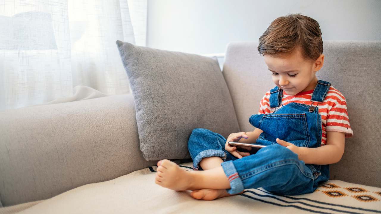 Niño usando una tableta junto a su madre, promoviendo el uso responsable de pantallas.