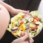 mujer embarazada feliz comiendo comida vegana saludable