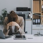 Persona muy afligida y encorvada en su escritorio