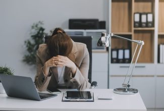 Persona muy afligida y encorvada en su escritorio