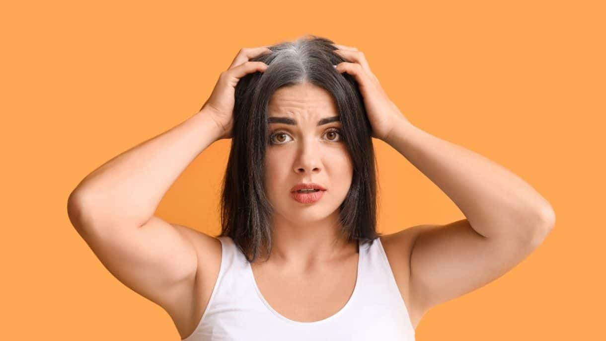 Mujer joven con canas visibles en la línea frontal del cabello