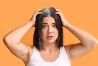 Mujer joven con canas visibles en la línea frontal del cabello