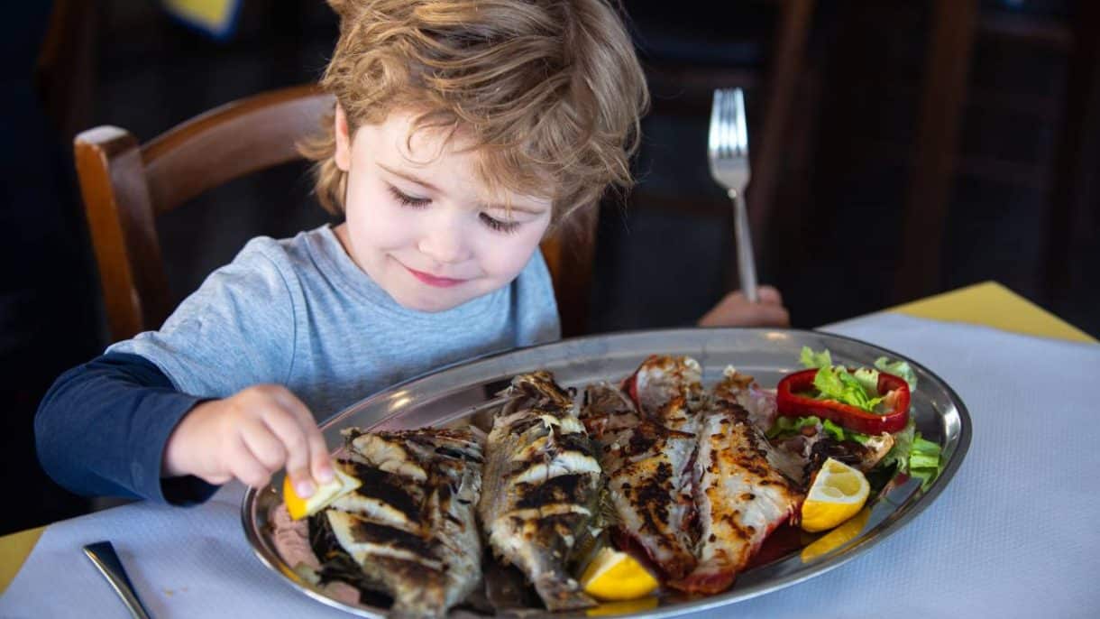 Niño comiendo pescado rico en omega-3 como protección contra la miopía.