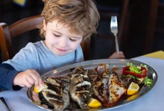 Niño comiendo pescado rico en omega-3 como protección contra la miopía.