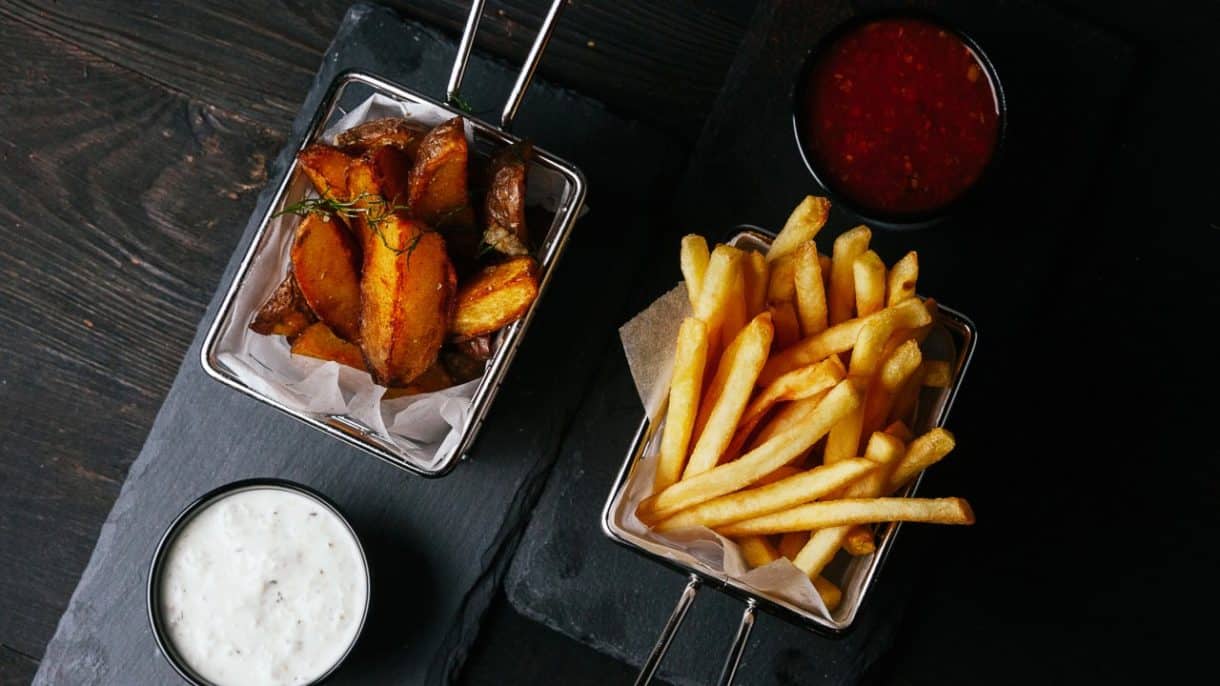 Papas fritas servidas en bandeja con fondo oscuro
