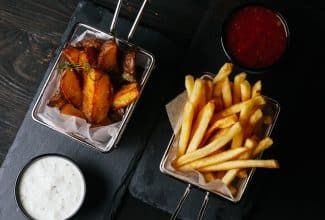 Papas fritas servidas en bandeja con fondo oscuro