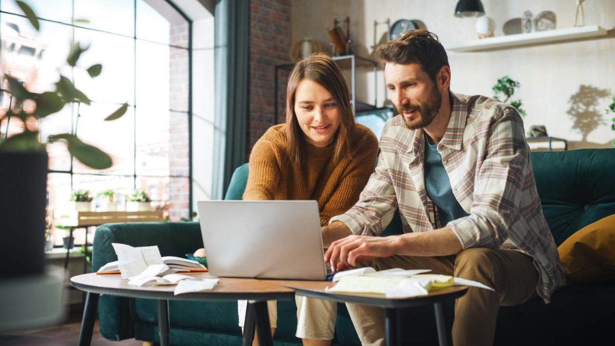 Pareja revisando sus gastos diarios y calculando en una libreta o app financiera.