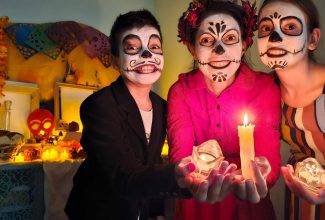 Familia sonriendo abrazados con decoración de Halloween y Día de Muertos en casa.