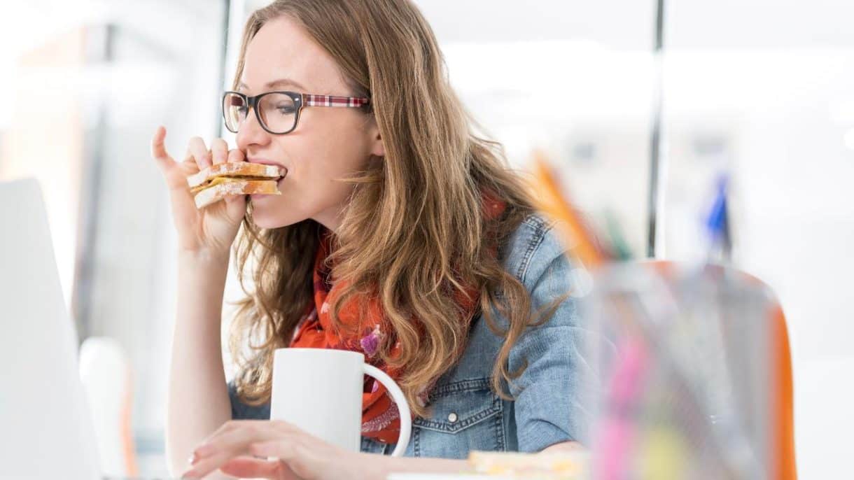 Mujer comiendo con prisa frente al ordenador