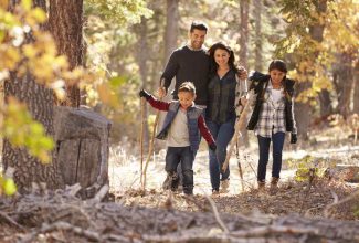 Familia con niños interactuando con la naturaleza, representando hábitos sencillos de crianza ecológica para criar hijos más conscientes.