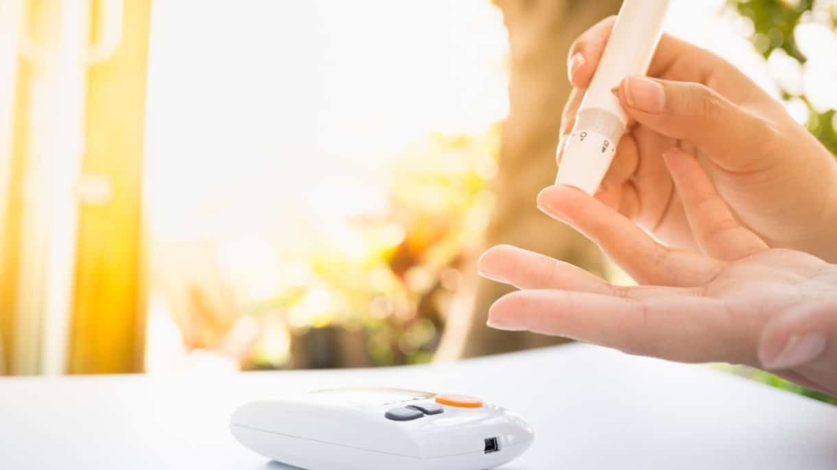 Persona revisando su nivel de azúcar en la sangre con un glucómetro, representando el control de la diabetes.