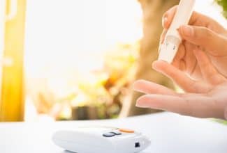 Persona revisando su nivel de azúcar en la sangre con un glucómetro, representando el control de la diabetes.