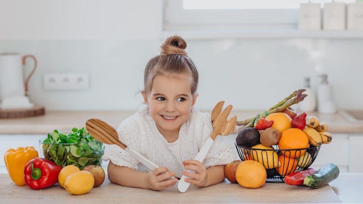 Niños comiendo variedad de frutas y verduras representando dietas vegetarianas y veganas