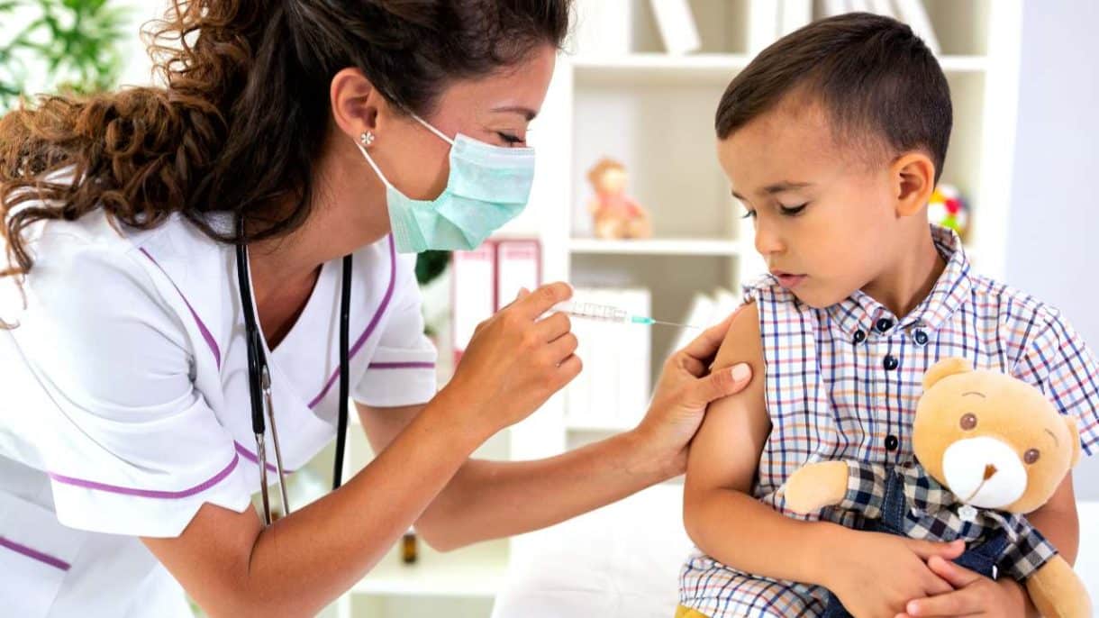 Profesional de la salud aplicando una vacuna a un niño pequeño para prevenir los casos de sarampión.