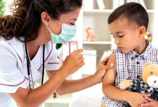 Profesional de la salud aplicando una vacuna a un niño pequeño para prevenir los casos de sarampión.