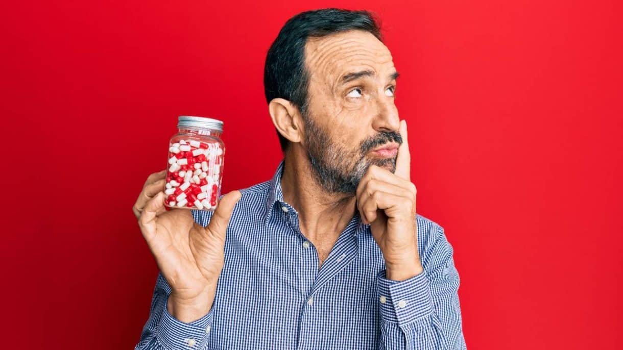 Persona sosteniendo un frasco de pastillas con gesto de reflexión, simbolizando la decisión de dejar los antidepresivos.
