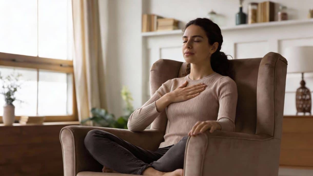Mujer practicando meditación de amor benevolente con una mano en el corazón.
