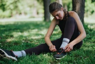 Mujer joven atándose las agujetas de los tenis para salir a correr como terapia contra la depresión.