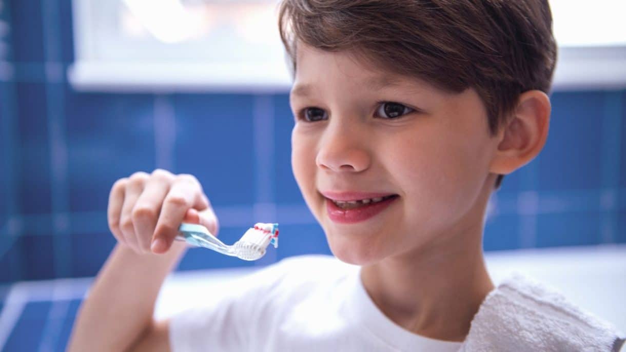 Niño cepillándose los dientes con buena salud dental