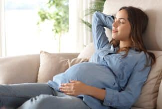 Mujer embarazada descansando en un interior fresco durante un día caluroso, representando la importancia de la protección térmica para la salud gestacional.