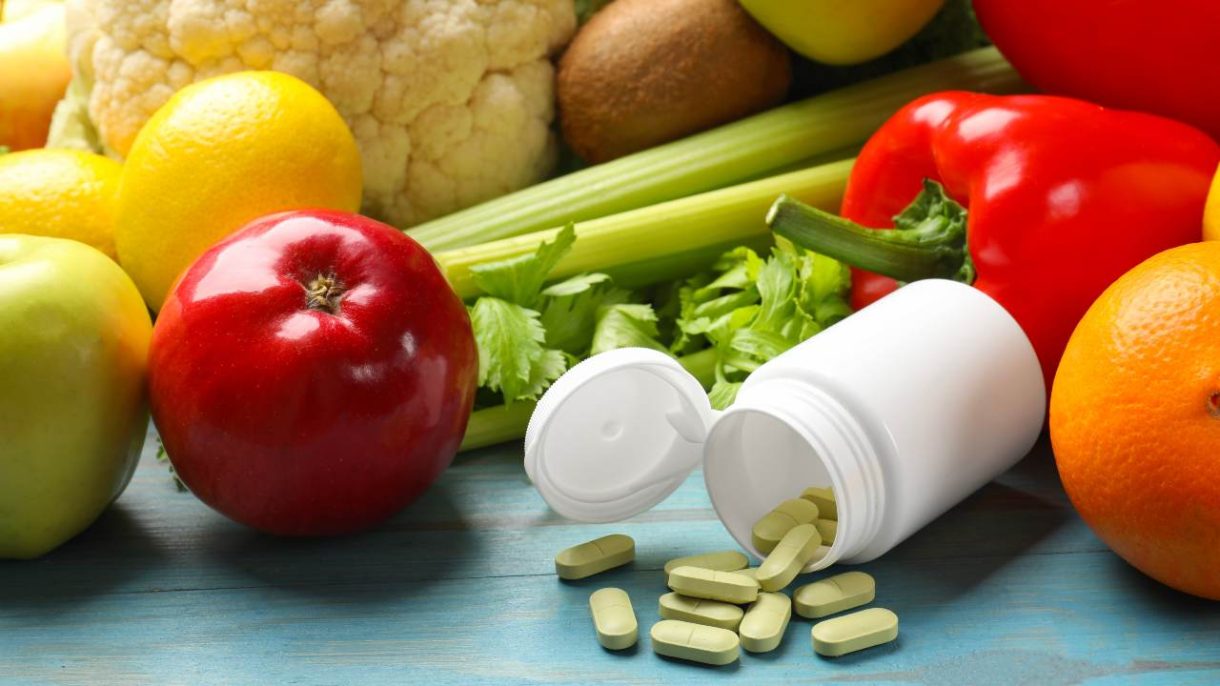 Pastillas y suplementos alimenticios junto a alimentos saludables