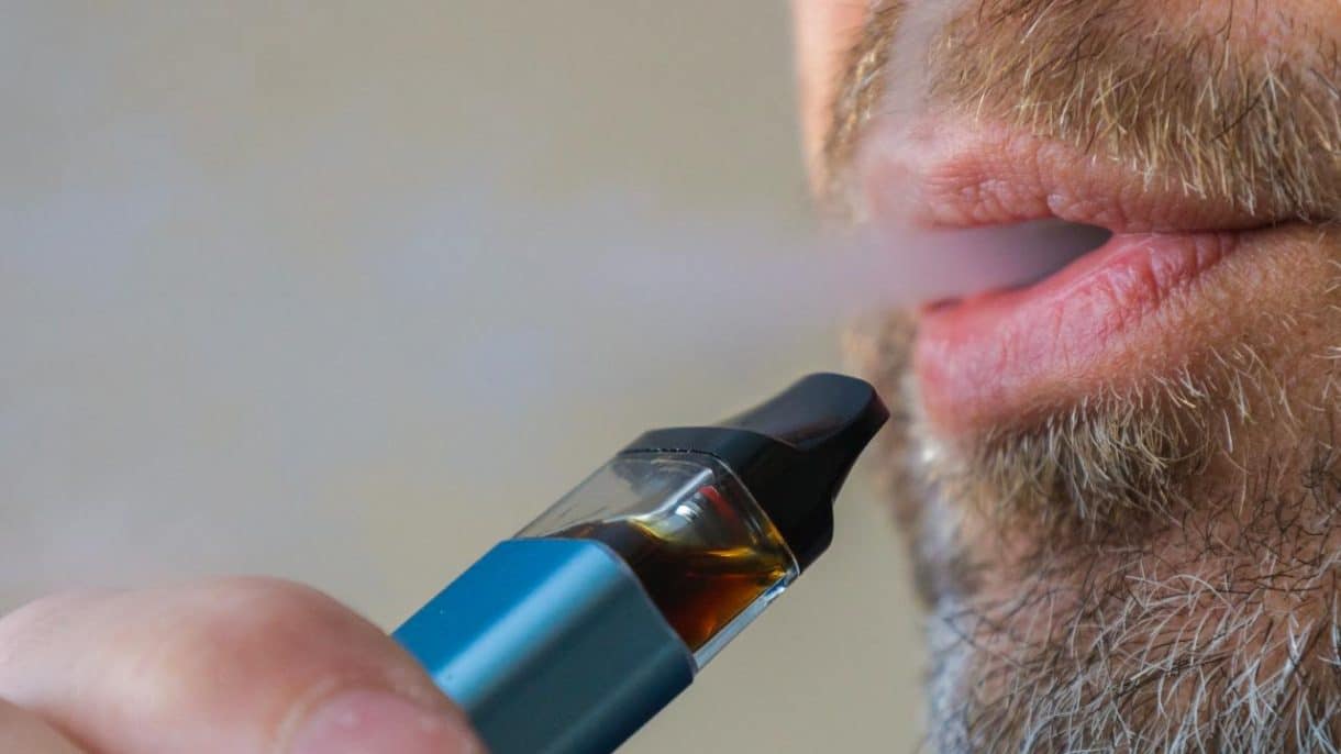 Persona vapeando cigarrillo electrónico con humo visible
