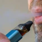 Persona vapeando cigarrillo electrónico con humo visible