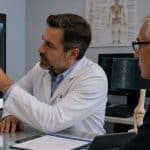 Hombre mayor revisando una radiografía ósea junto a un especialista