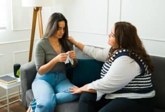 Mujer acompañando en silencio a una amiga triste mientras conversan en un sofá.