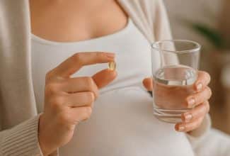 Mujer embarazada tomando un suplemento de vitamina D mientras sostiene su vientre