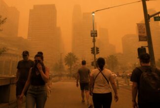 Personas caminando en una ciudad cubierta por humo procedente de incendios forestales