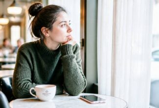 Mujer pensativa mirando su teléfono mientras piensa de forma persistente en una persona